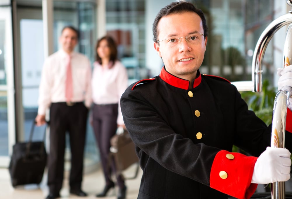 Hotel bellboy carrying the luggage of a business couple