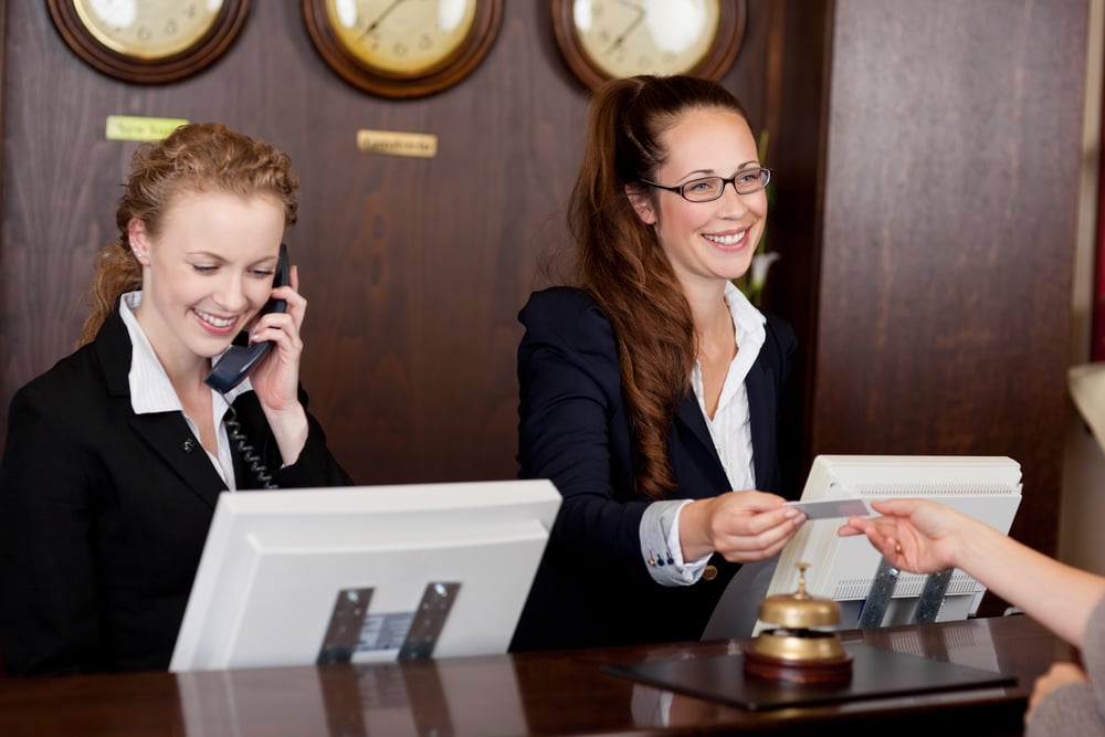 Front desk employees at hotel, taking payment from guests who are checking in.